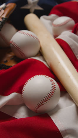 Vertical-Video-Close-Up-Baseball-Still-Life-With-Bat-And-Ball-On-American-Flag